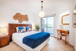 a bedroom with a bed and a desk and a window at Clube Albufeira: 2BR Prime Holidays Retreat in Albufeira