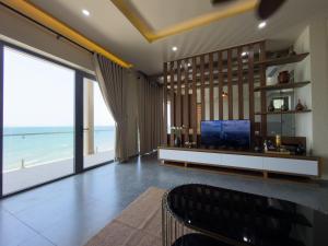 a living room with a television and a view of the beach at SUNSHINE BEACH Resort in Mui Ne