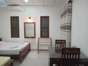 a room with a bed and a table and a mirror at Mihinsa Guest in Kosgoda