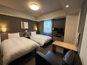 a hotel room with two beds and a couch at Hotel Route-Inn Kanuma Inter in Kanuma +40 photos