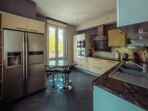 a kitchen with a stainless steel refrigerator and a table at Le Grand Rivage in Verdun-sur-Meuse