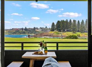 a table with a bottle of wine and a window at Kove Apartment - B02 in Kiama