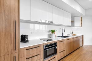 a kitchen with wooden cabinets and white appliances at Kove Apartment - B02 in Kiama