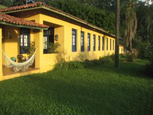 a yellow house with a hammock outside of it at Pousada Casa Da Fazenda in Paraisópolis