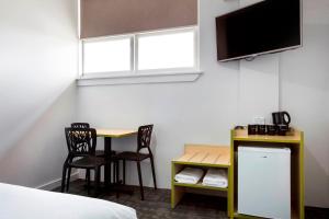 a hotel room with a desk and a table and a tv at Nightcap at Caringbah Hotel in Caringbah