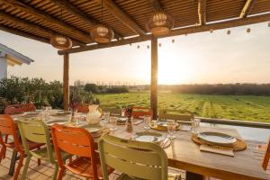 a long wooden table with chairs and a view of a field at Casa Terracotta with Private Pool in Comporta