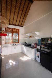 a kitchen with white cabinets and a black refrigerator at Tegal Wangi Penebel in Penebel