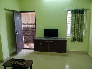a living room with a tv on a cabinet and a mirror at Vihaasam Homestay in Thanjāvūr