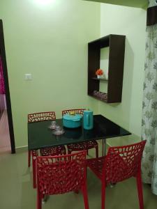 a dining room with a black table and red chairs at Vihaasam Homestay in Thanjāvūr