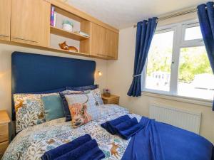 a bedroom with a bed with a blue headboard and a window at 25 Foxburrow Hang in Great Yarmouth