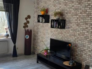 a living room with a tv and a brick wall at Märchenwerkstatt in Netphen