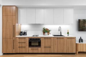 a kitchen with wooden cabinets and a sink at Kove Apartment - G01 in Kiama +3 photos