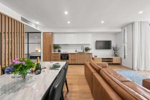 a kitchen and living room with a table and a couch at Kove Apartment - G01 in Kiama