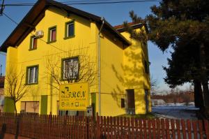a yellow house with a sign in front of it at Sobe Tron Palić in Palić