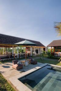 a pool with two lounge chairs and an umbrella at Tegal Wangi Penebel in Penebel
