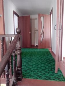 a hallway with a green carpet and a wooden railing at Тумар дом in Tamga