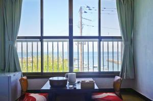 a room with a table in front of a large window at 海凪旅館 in Tateyama