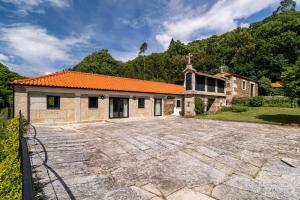 an old stone house with an orange roof at Eira Country House in Ponte de Lima