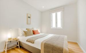 a white bedroom with a large bed with orange pillows at Espinho Beach 4 Stays with Terrace in Espinho
