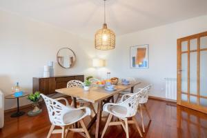 a dining room with a wooden table and white chairs at São Félix Seaside Oasis in São Félix da Marinha