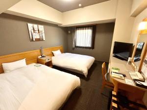a hotel room with two beds and a desk with a computer at Hotel Route-Inn Kikugawa Inter in Kikugawa