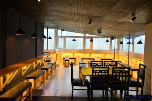a dining room with tables and chairs and windows at Friends By Alizeh 2 0 Mcleodganj in Dharamshala