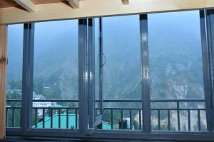 a view of a mountain through a window at Friends By Alizeh 2 0 Mcleodganj in Dharamshala