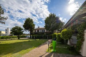 a house with a green trash can in the yard at Residence Borgo Stella Marina in Bibione