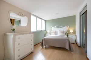 a bedroom with a bed with a dresser and a mirror at Espinho Retreat with Balcony in Espinho