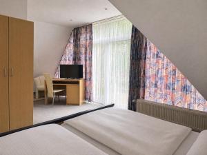 a bedroom with a bed and a desk and a window at Hotel Bölke in Wunstorf
