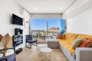 a living room with a couch and a large window at Blue Breeze Espinho | Pool View, Gym & Balcony in Espinho