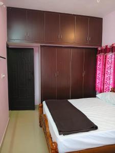 a bedroom with a bed with wooden cabinets at Vihaasam Homestay in Thanjāvūr