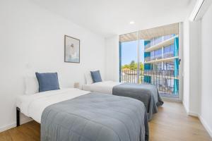 two beds in a room with a large window at Olivia Maresia Homestay in Espinho