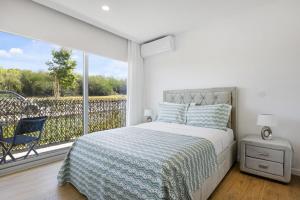 a white bedroom with a bed and a large window at Sunny Stays Espinho | Balcony & Pool in Espinho