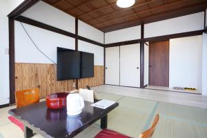 a room with a table and a flat screen tv at 海凪旅館 in Tateyama