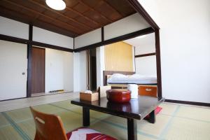 a room with a bed and a table and a bed at 海凪旅館 in Tateyama