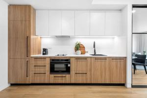 a kitchen with wooden cabinets and a stove top oven at Kove Apartment - G02 in Kiama