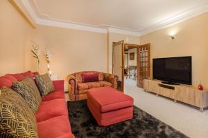 a living room with a red couch and a tv at Cantinho em Cascais, Spacious 3BR with Balconies in Cascais