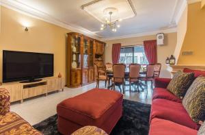 a living room with a red couch and a television at Cantinho em Cascais, Spacious 3BR with Balconies in Cascais