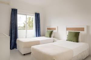 two beds in a white room with a window at Prainha Family Fun | Balcony & Pools in Alvor
