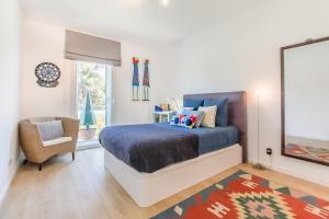 a bedroom with a bed and a chair and a window at Luxury Beach Experience in Lisbon in Oeiras