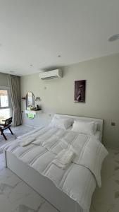 a white bedroom with a large white bed in it at Reef ALjabal Rest in Minthār +3 photos