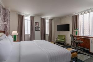 a hotel room with a bed and a chair and a television at Le Meridien Indianapolis in Indianapolis