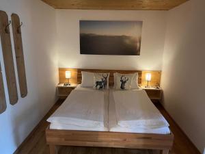 a bedroom with a large white bed with two lamps at Apartment with Alpine views in Fügenberg