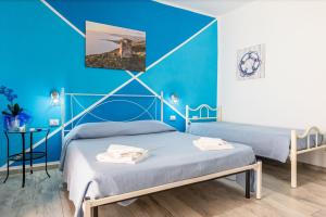 two beds in a room with blue walls at Perla Marina Rooms in Realmonte