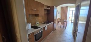 a kitchen with wooden cabinets and a dining room at Apartment SunSet rezort - sea wiew in Pomorie