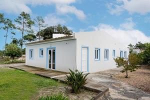 a white house with blue windows and a yard at Pinhal da Praia em Melides in Quinta da Cascalheirinha