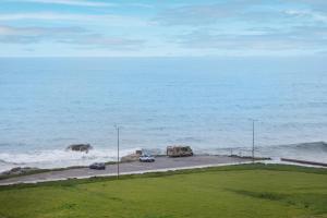 two cars parked on a road next to the ocean at Sal D’Ouro Skyline & Sea Views in Canidelo +66 photos