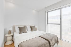 a white bedroom with a large bed and a window at Sal D’Ouro Skyline & Sea Views in Canidelo