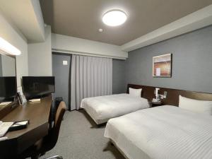 a hotel room with two beds and a desk at Hotel Route-Inn Ina Inter in Minamiminowa
